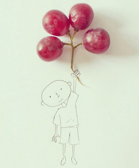 DRawn boy on a paper sheet holdingbunch of grapes as balloons.