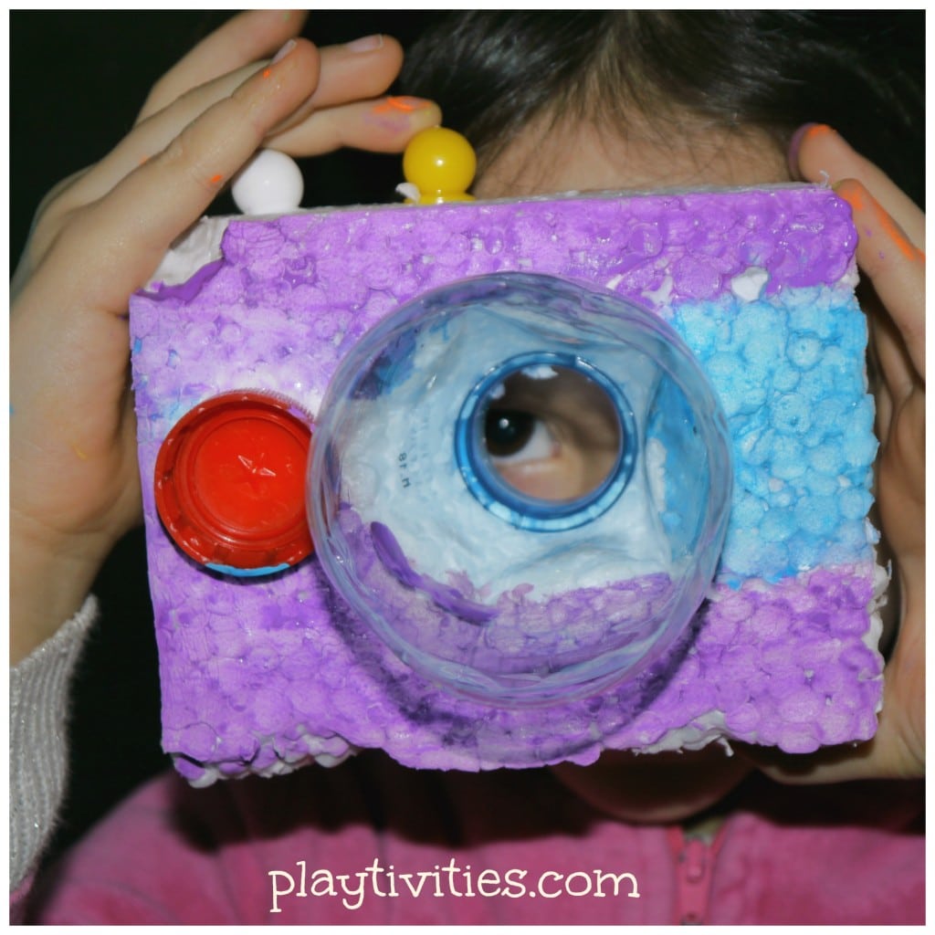 Young girl holding a styrofoam toy camera.