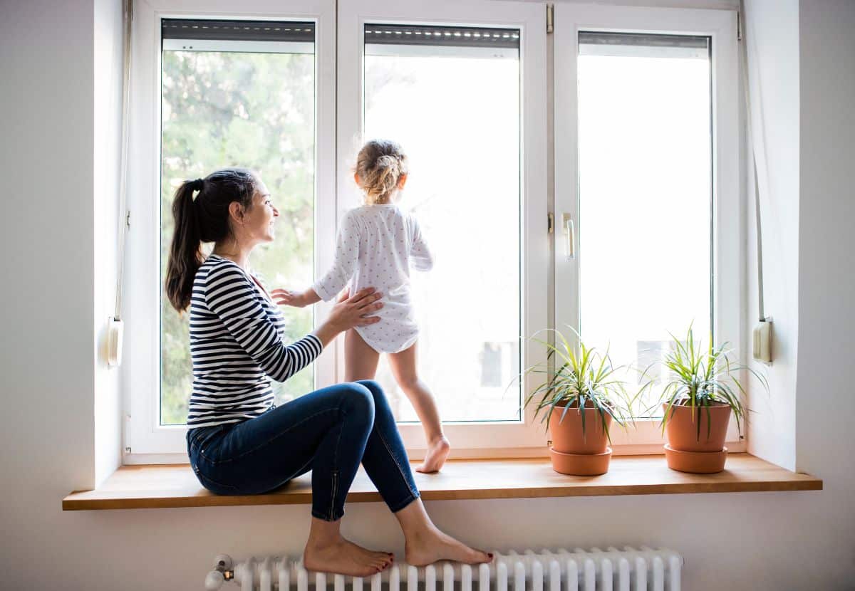 Young woman playing with her daughter near a window.