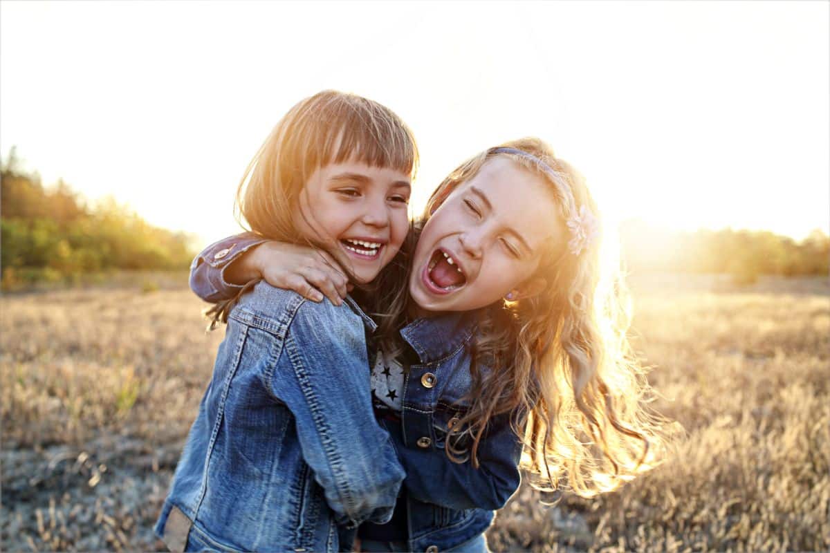 Two young girl laughing and hugging each other.