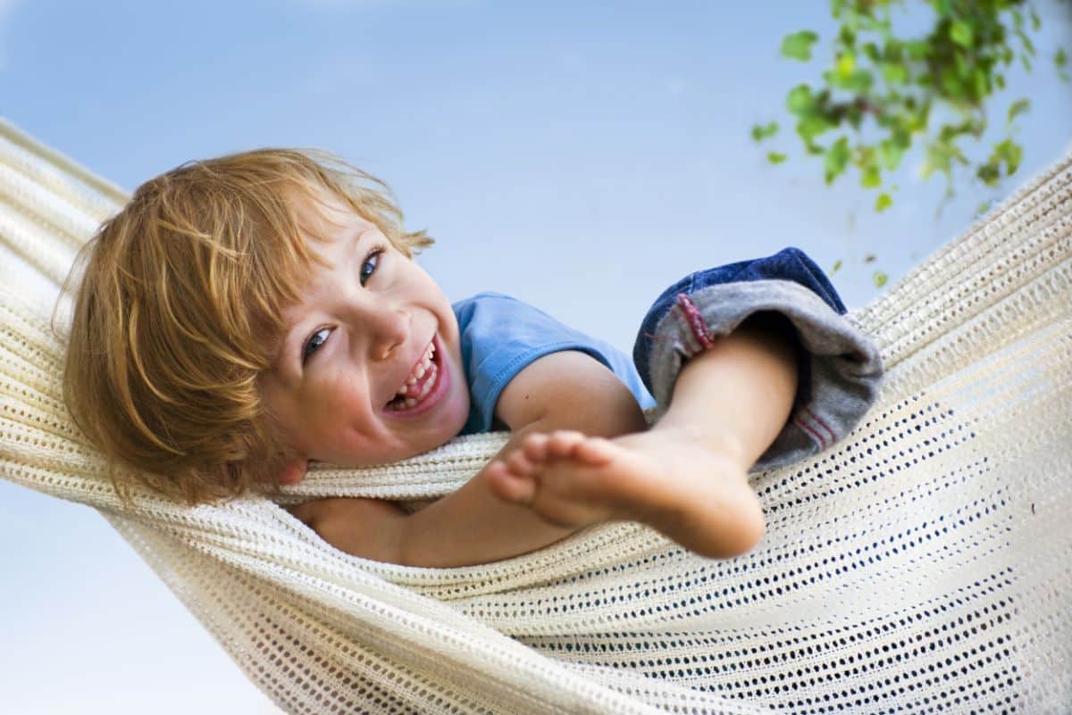 Young children in a hammock laughing.