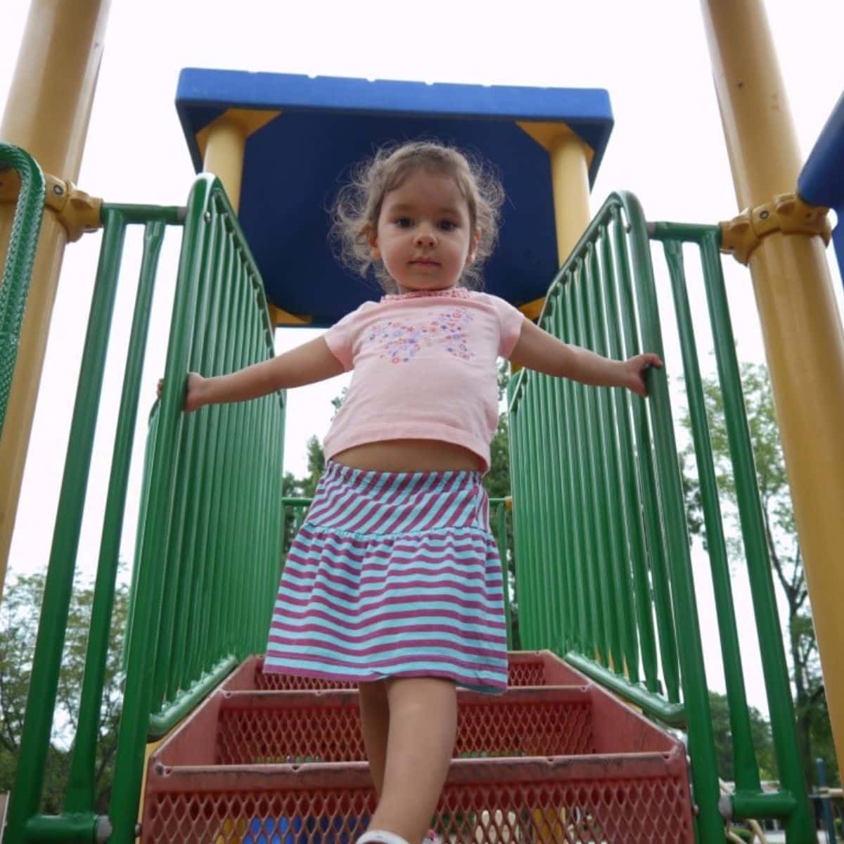 Young girl walking down on a playground stairs.