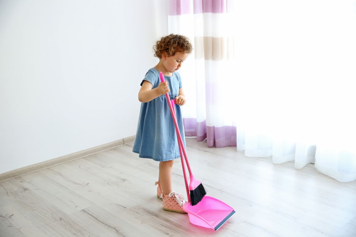Young girl sweeping a room floor.