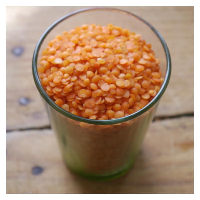 Glass cup of lentils on a wooden table.