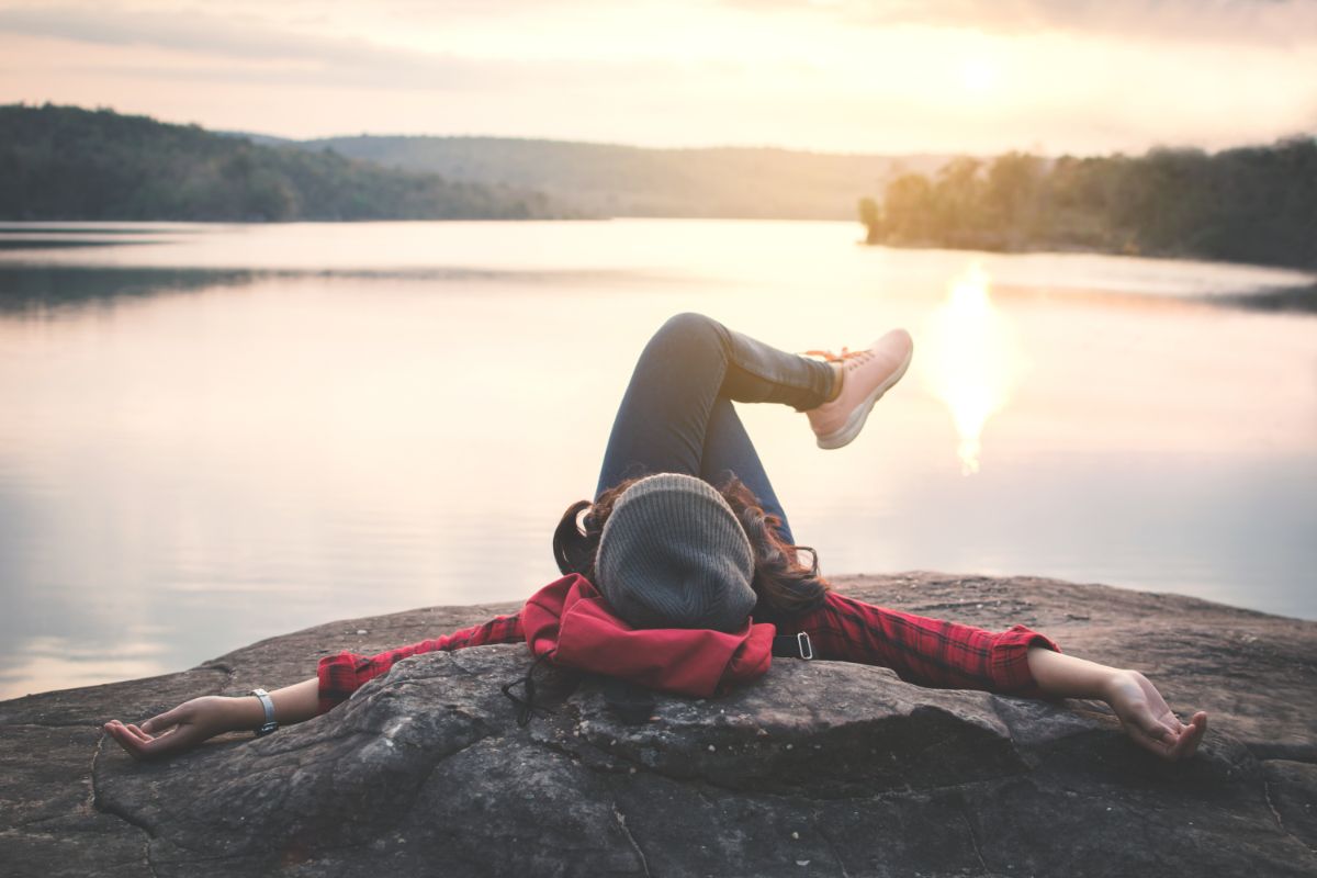 Young woman lying on a rock near a lake.