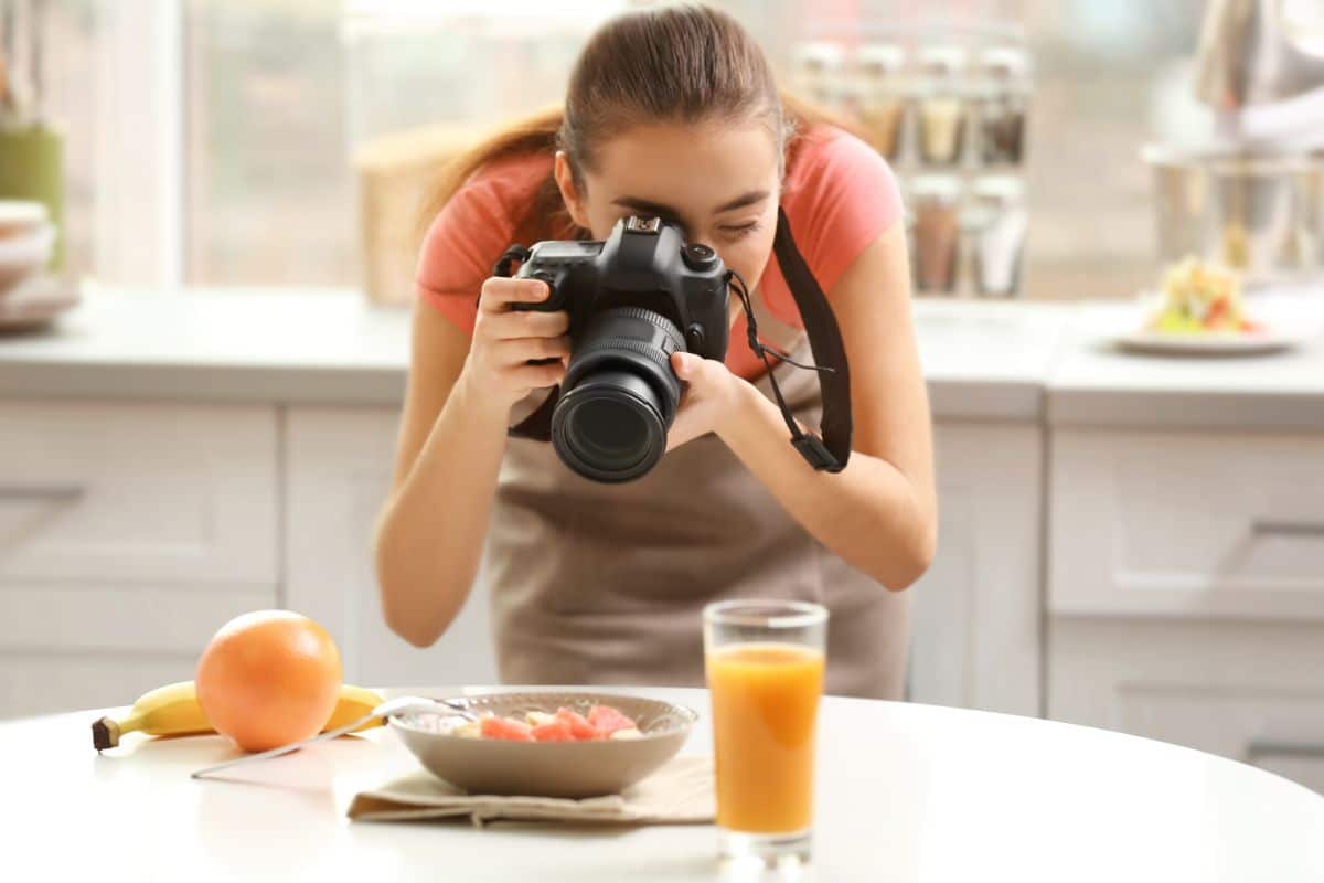 Young woman taking a picture of food on a table.