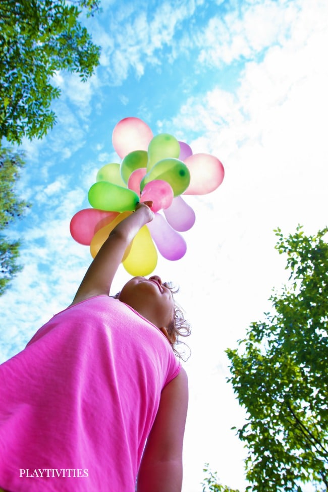 Young girl in pink dress holding balloons.