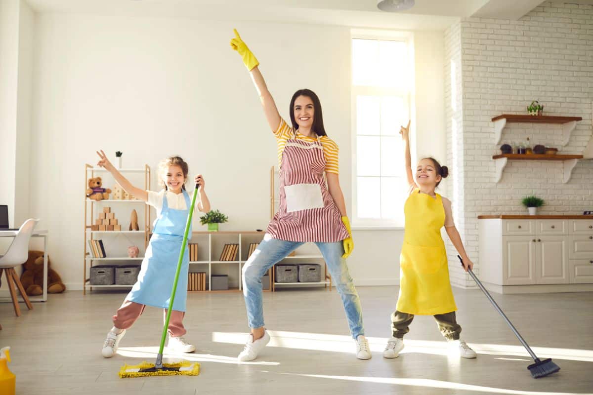 Mother with two daughters dancing while cleaning a house.