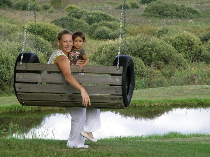 Mother and daughter spending time near a lake on a swing.