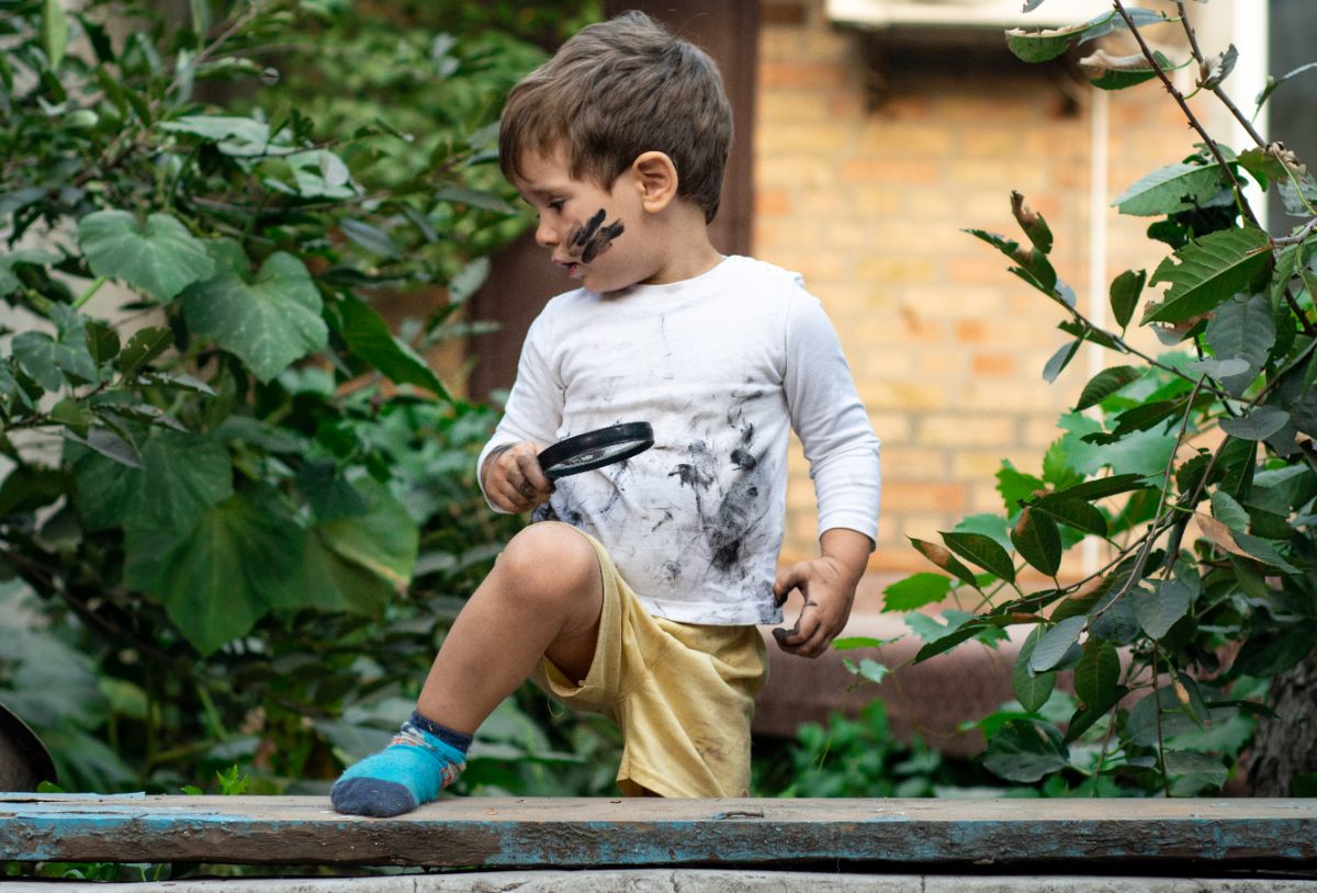 Toddler with dirty clothes playing outdoor.