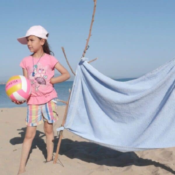 Young girl holding a ball on a beach next to diy net