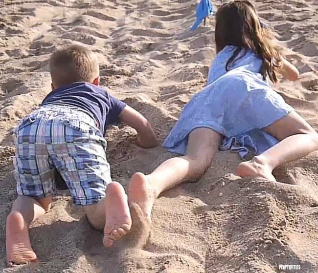 Two kids crawling on a beach.