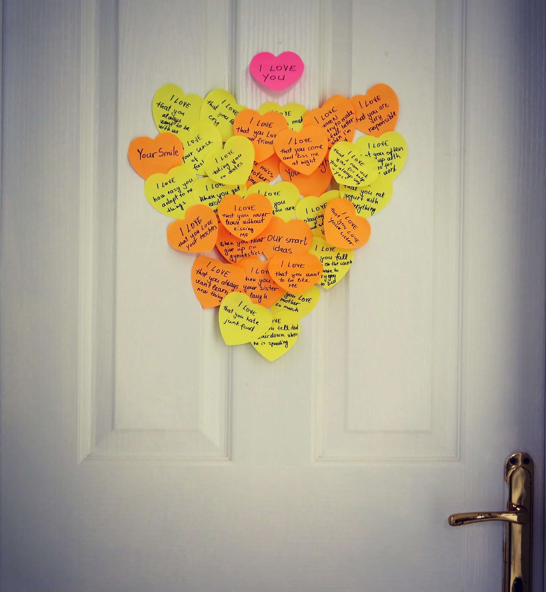 Bunch of sticky notes in a shape of heart on a door.