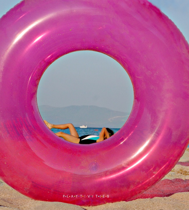 Girl in a pink loop on a beach.