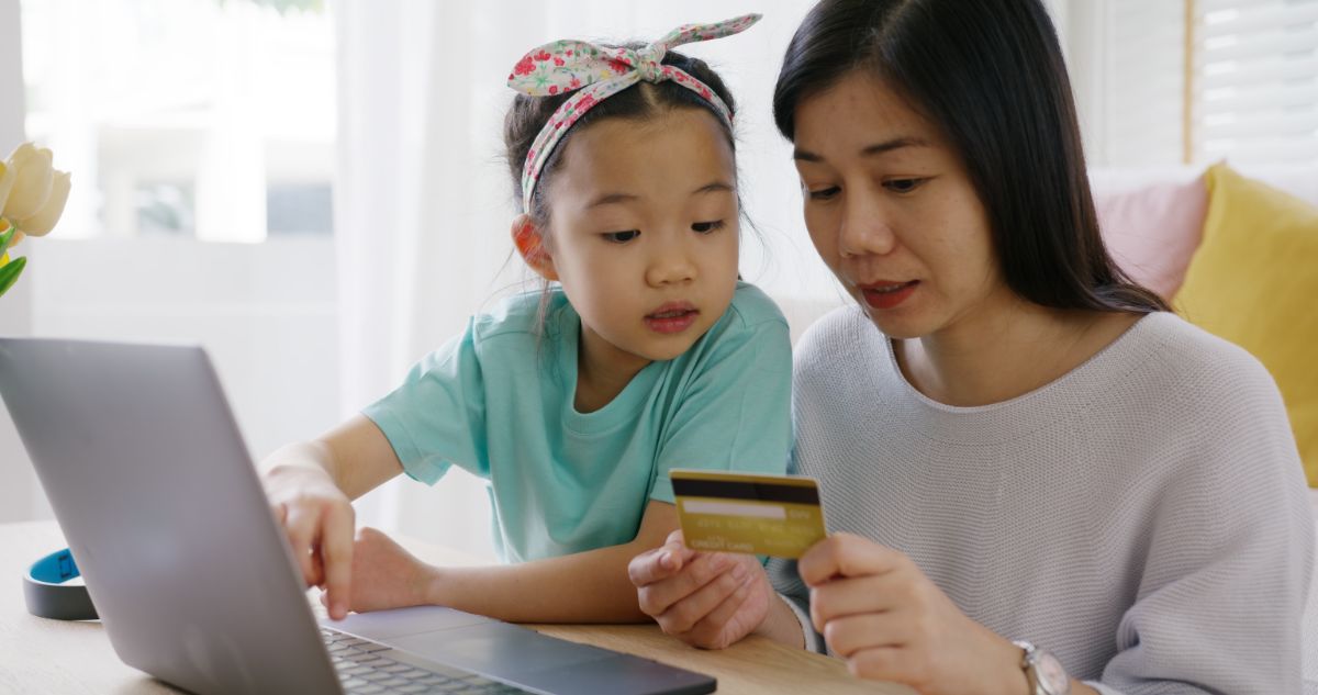 Young daughter helping mom pay through credit card online.