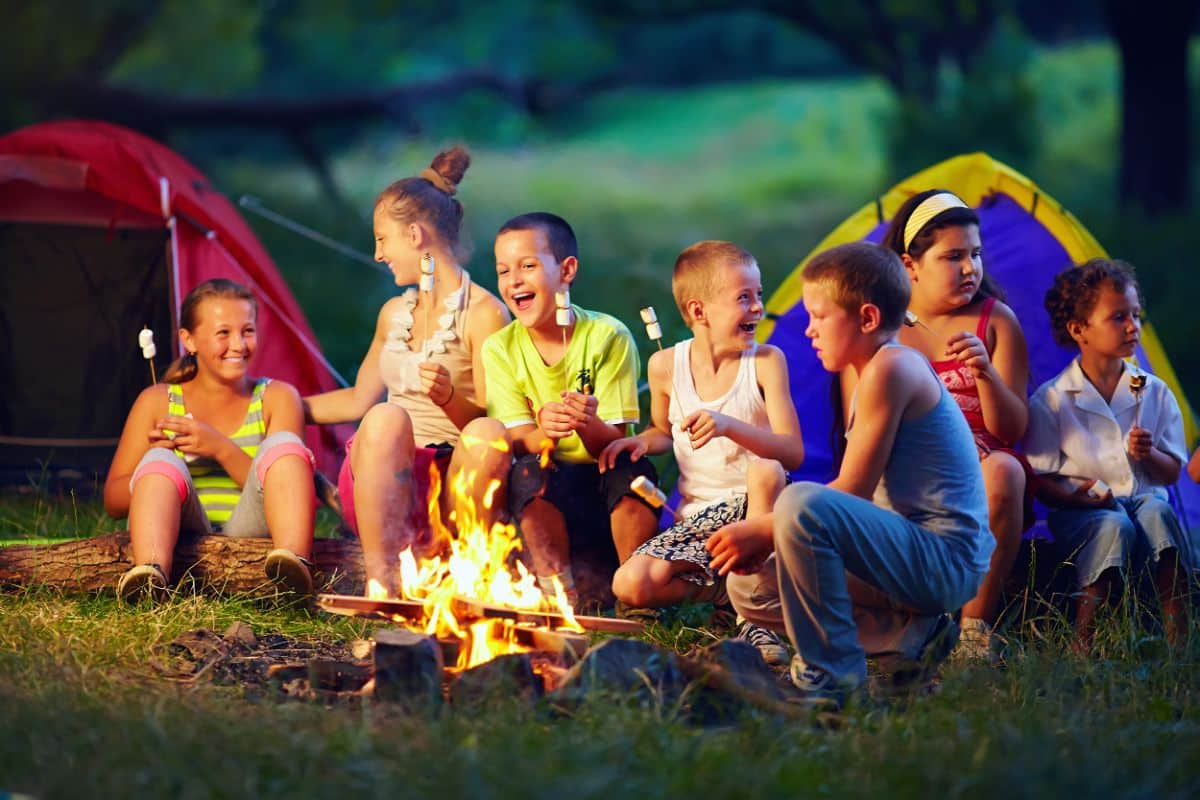 Bunch od kids roasting marshmallows on a bonfire.