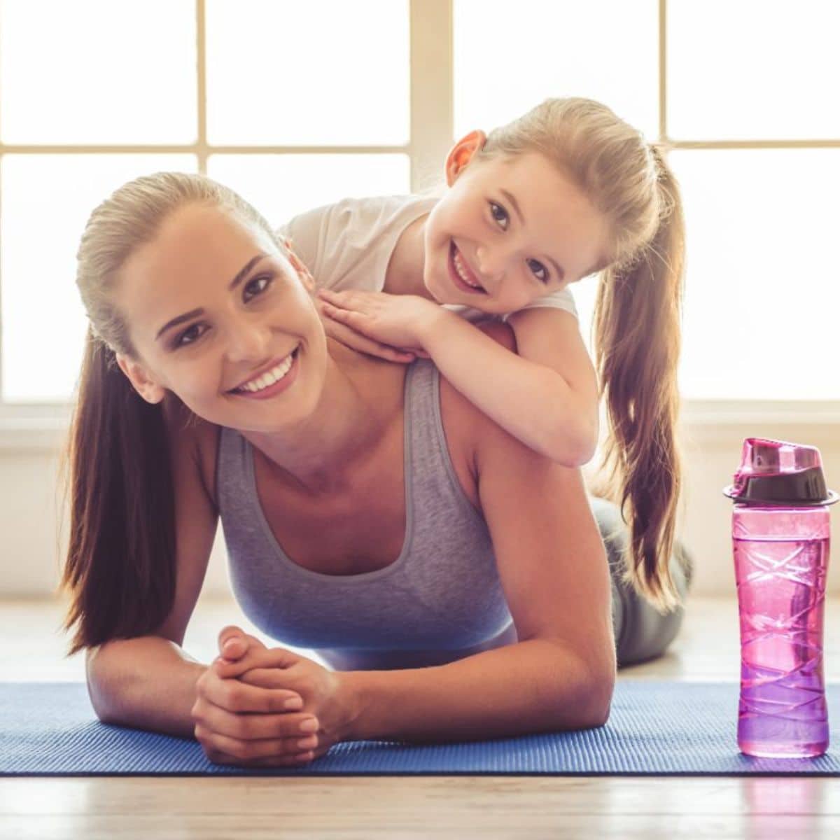 Mother and daughter working out together on a yoga mat.