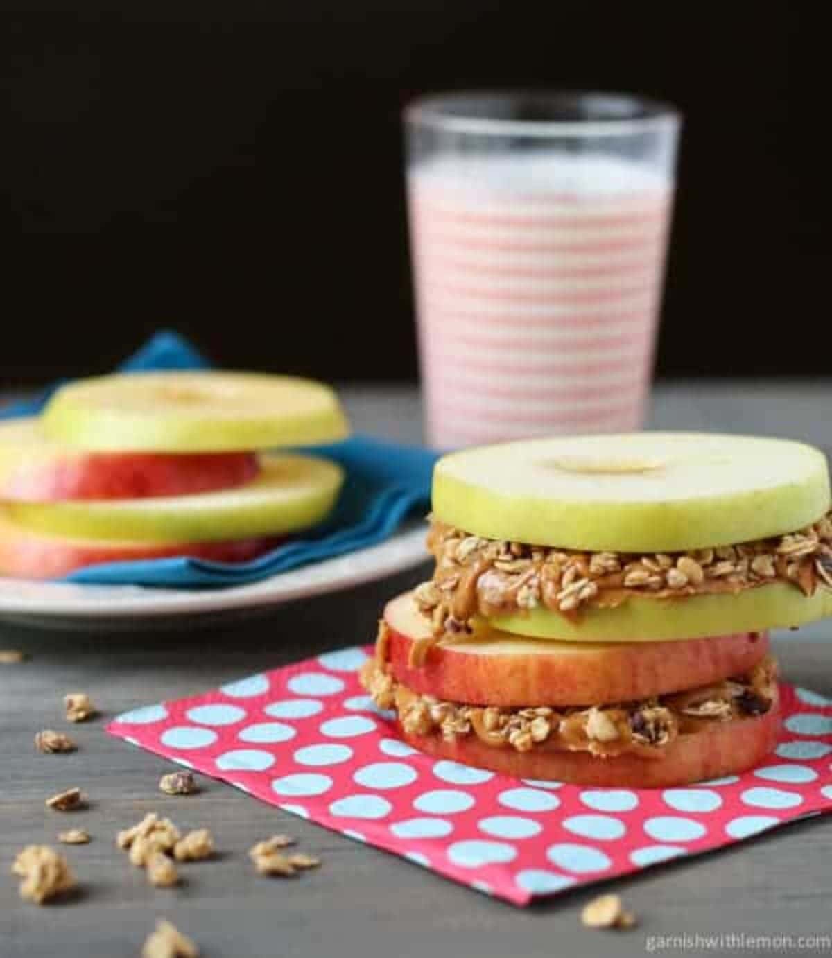 Apple sandwiches with peanut butter and granola on a table.