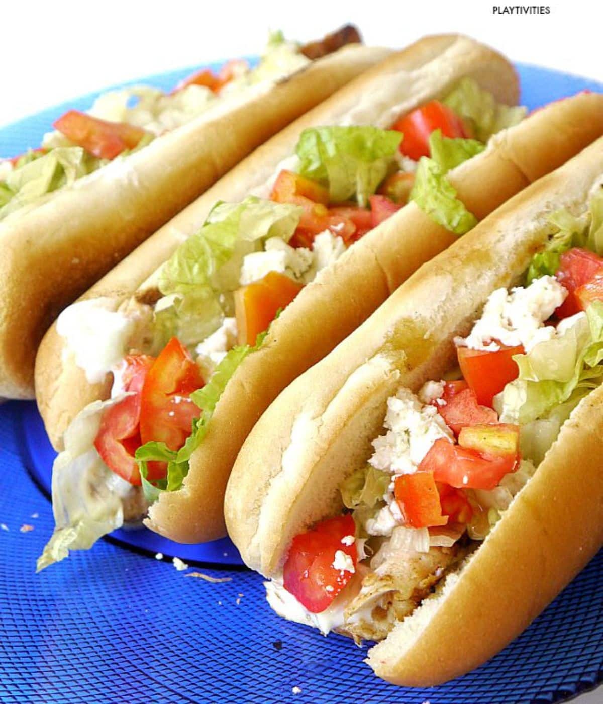 Three grilled chicken hot dogs on a blue plate.