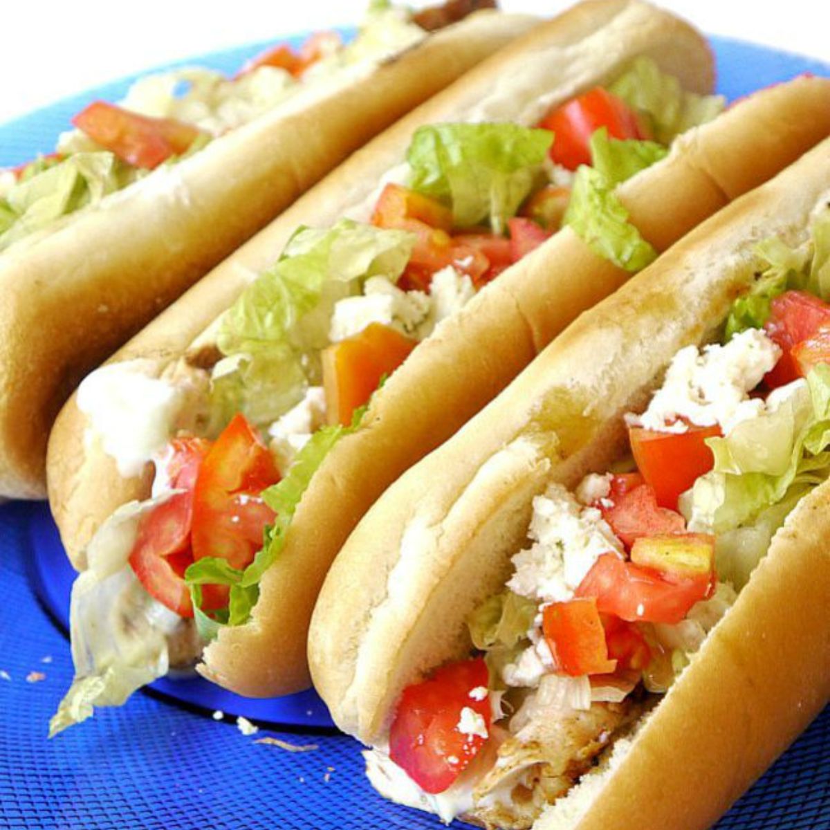Three grilled chicken hot dogs on a plate.