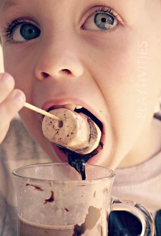 Boy eating a hot chocolate stick.