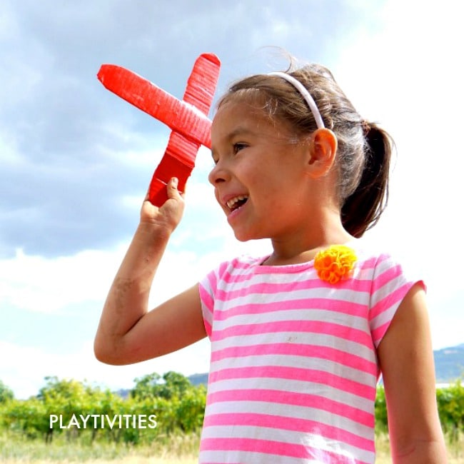 Young girl holding a homemade cardboard boomerang.