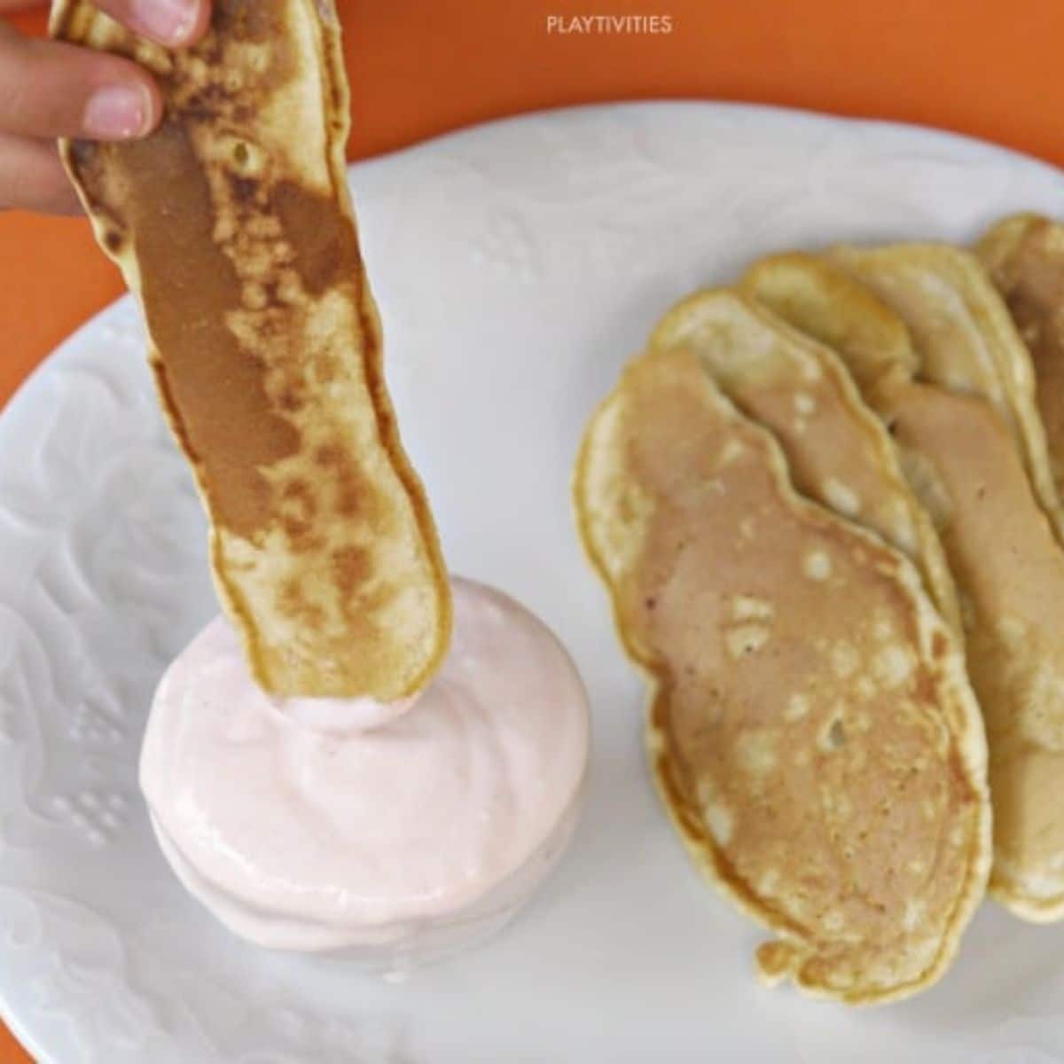 Pancake dippers with yogurt on a plate.