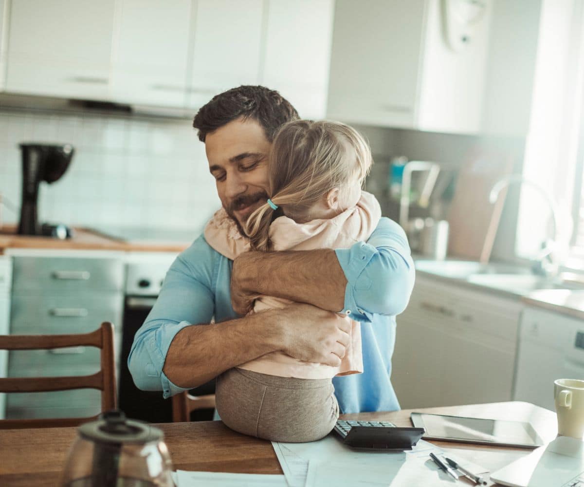Father hugging his little daughter in a kitchen.