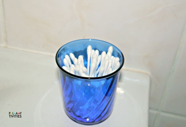 Blue cup full of q-tips.