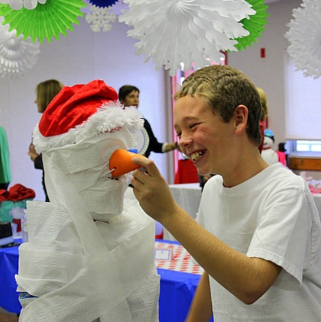 Laughing boy touching a homemade snowman.