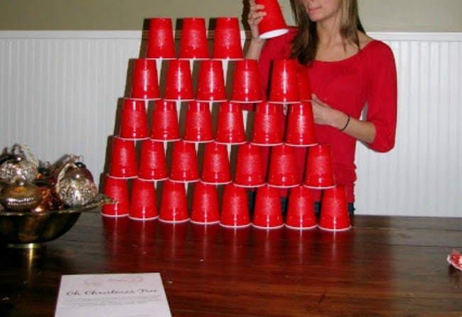 Girl playing a cups game on a table.
