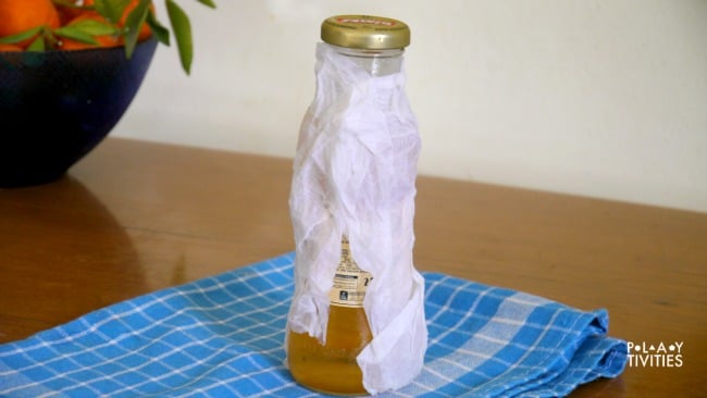Wrapped jar of apple juice on a table.