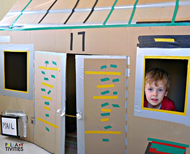 Young boy in homemade cardboard house
