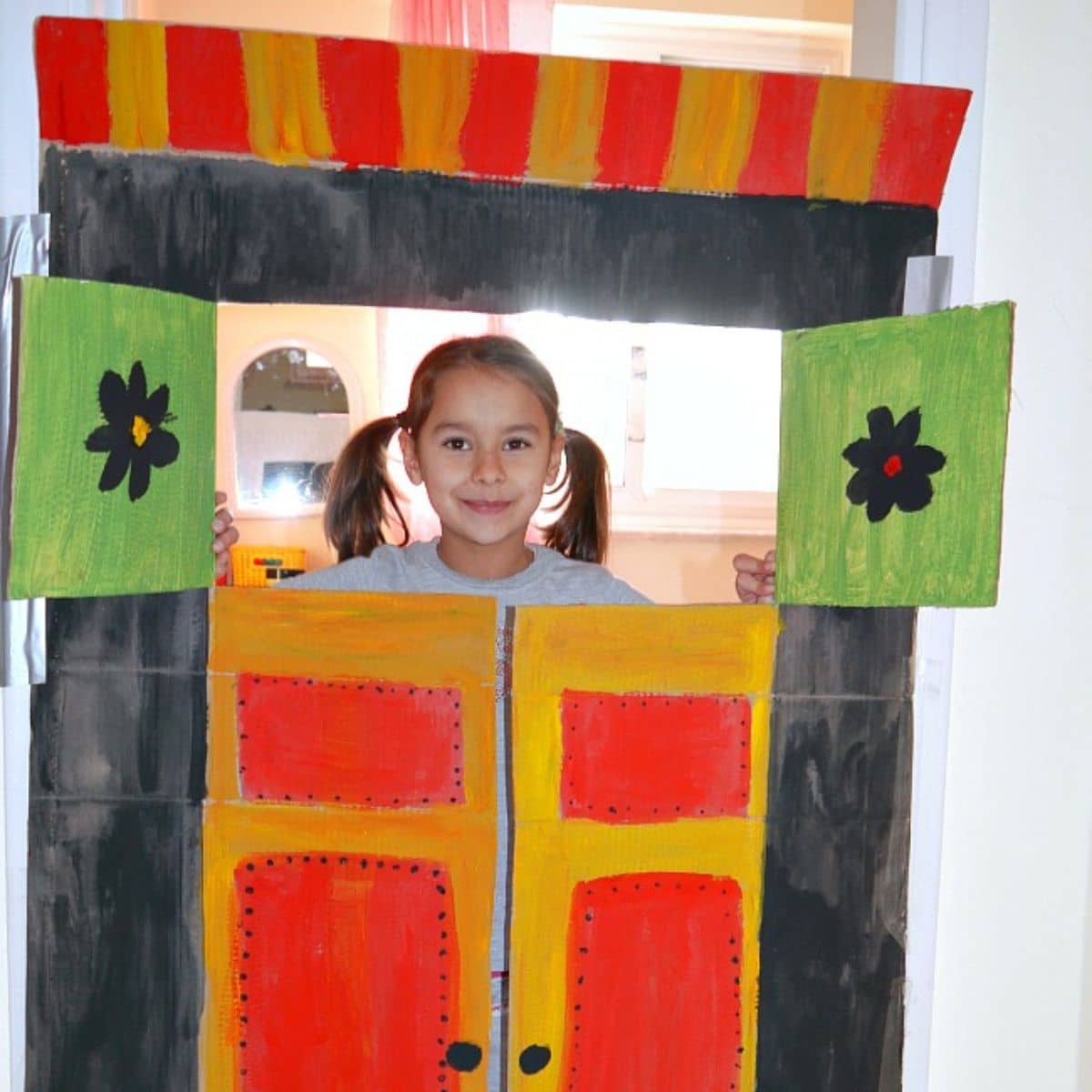 Young girl in diy puppet theater from carboard.