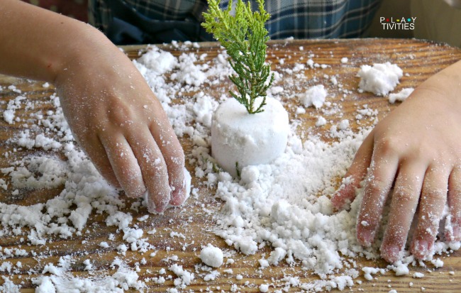 Hands playing with a fake snow on a table.