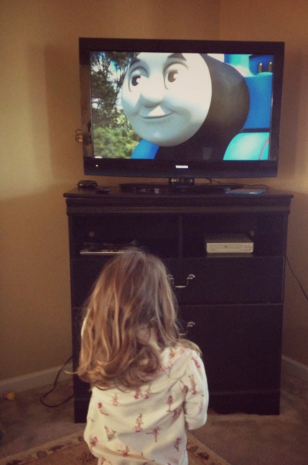 Young girl watching Thomas train movie on a tv.
