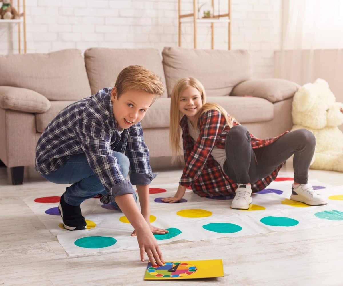 Brother and sister playing  twister in a living room.