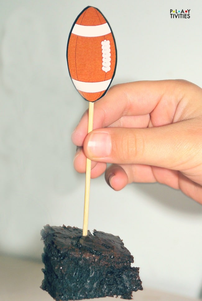 Hand holding a game brownie by a stick.
