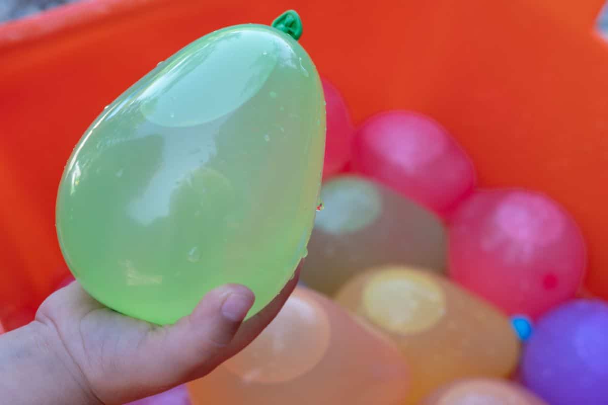 Hand holding a green water balloon.