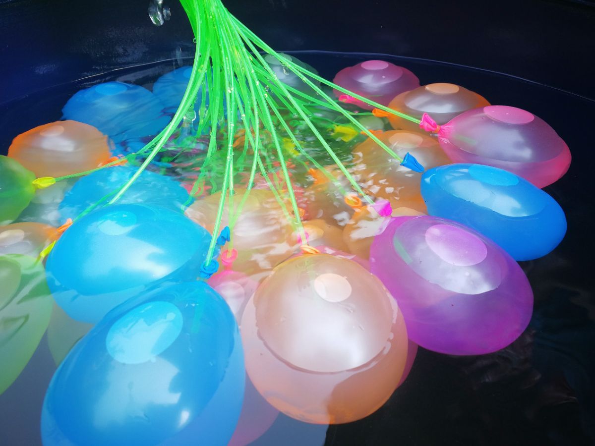 Bunch of colorful water balloons in water.