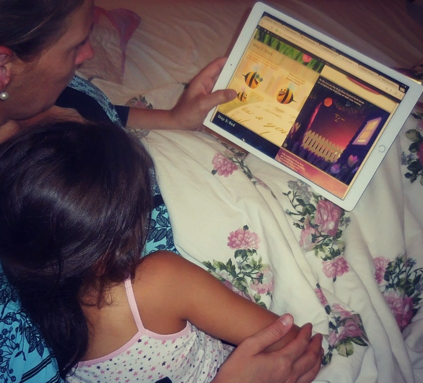 Mother and daughter lying in a bed and watching a tablet.