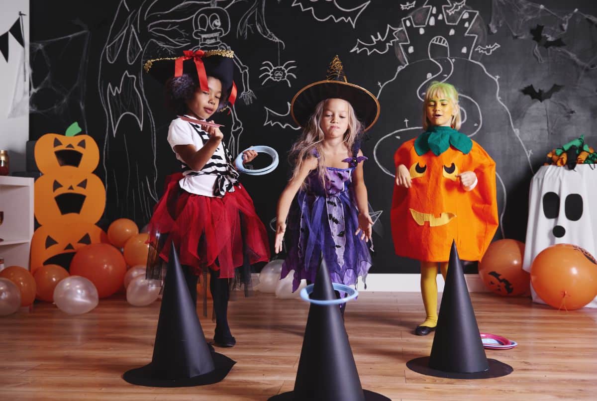 Three kids in halloween costumes playing a halloween game together.