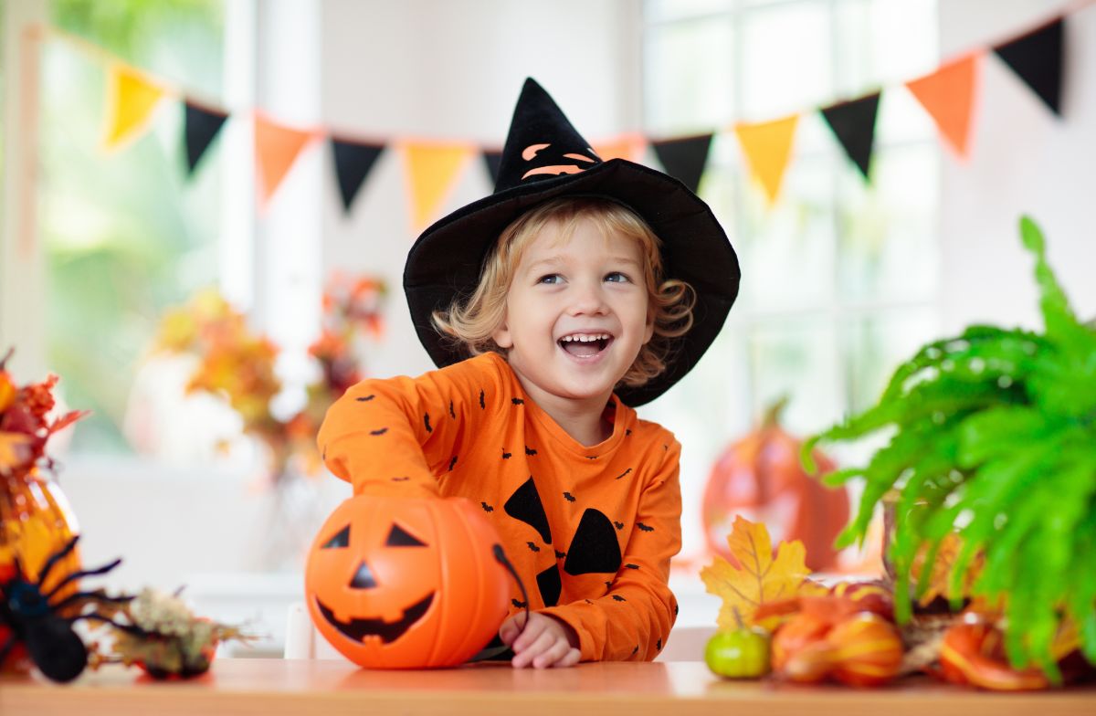 Young boy in a halloween costume putting hand in a pumpkin.