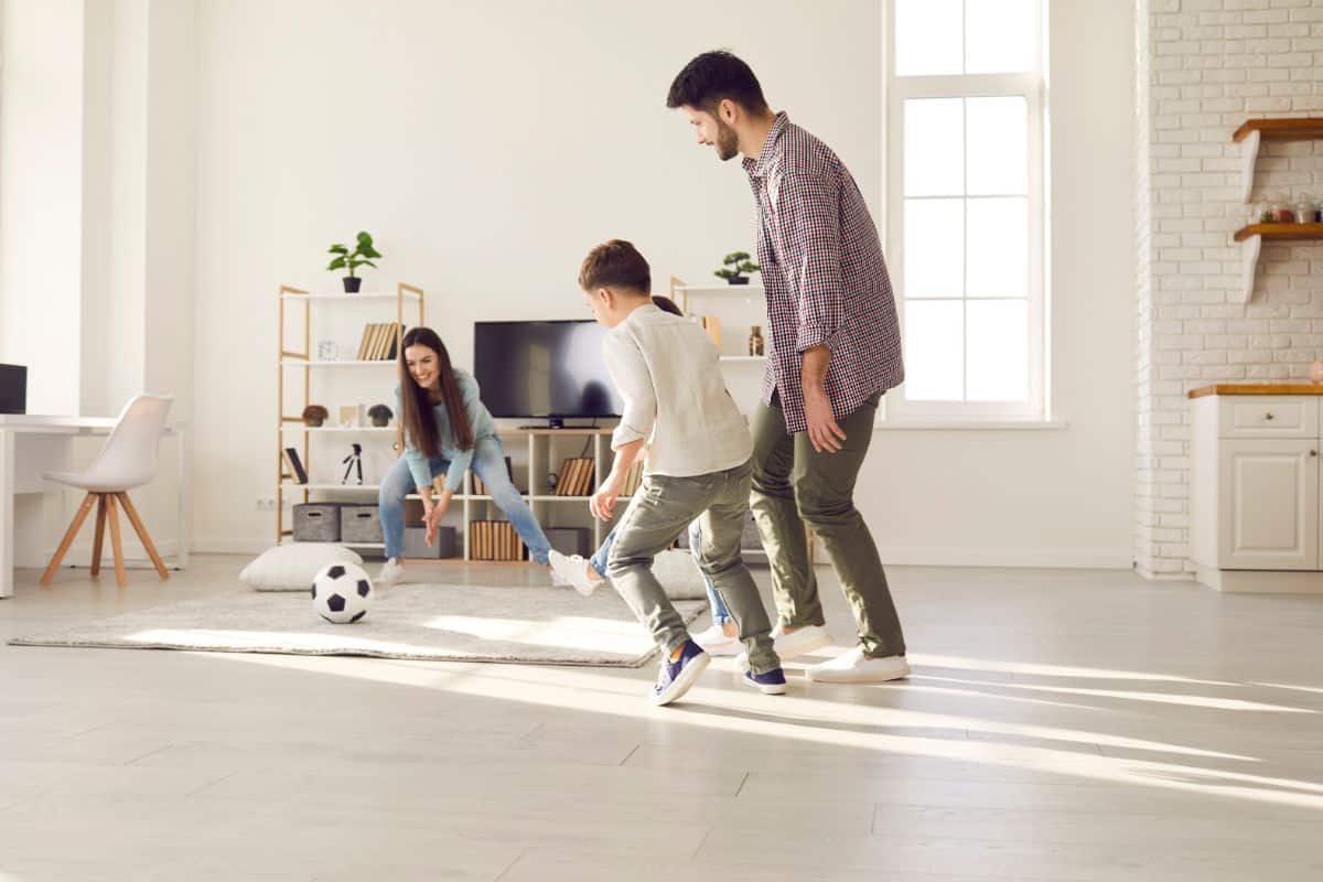 Young family playing a soccer in a living room.