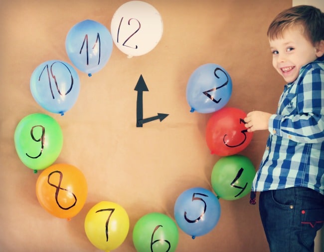 Young boy standing next to a clock made from ballons.