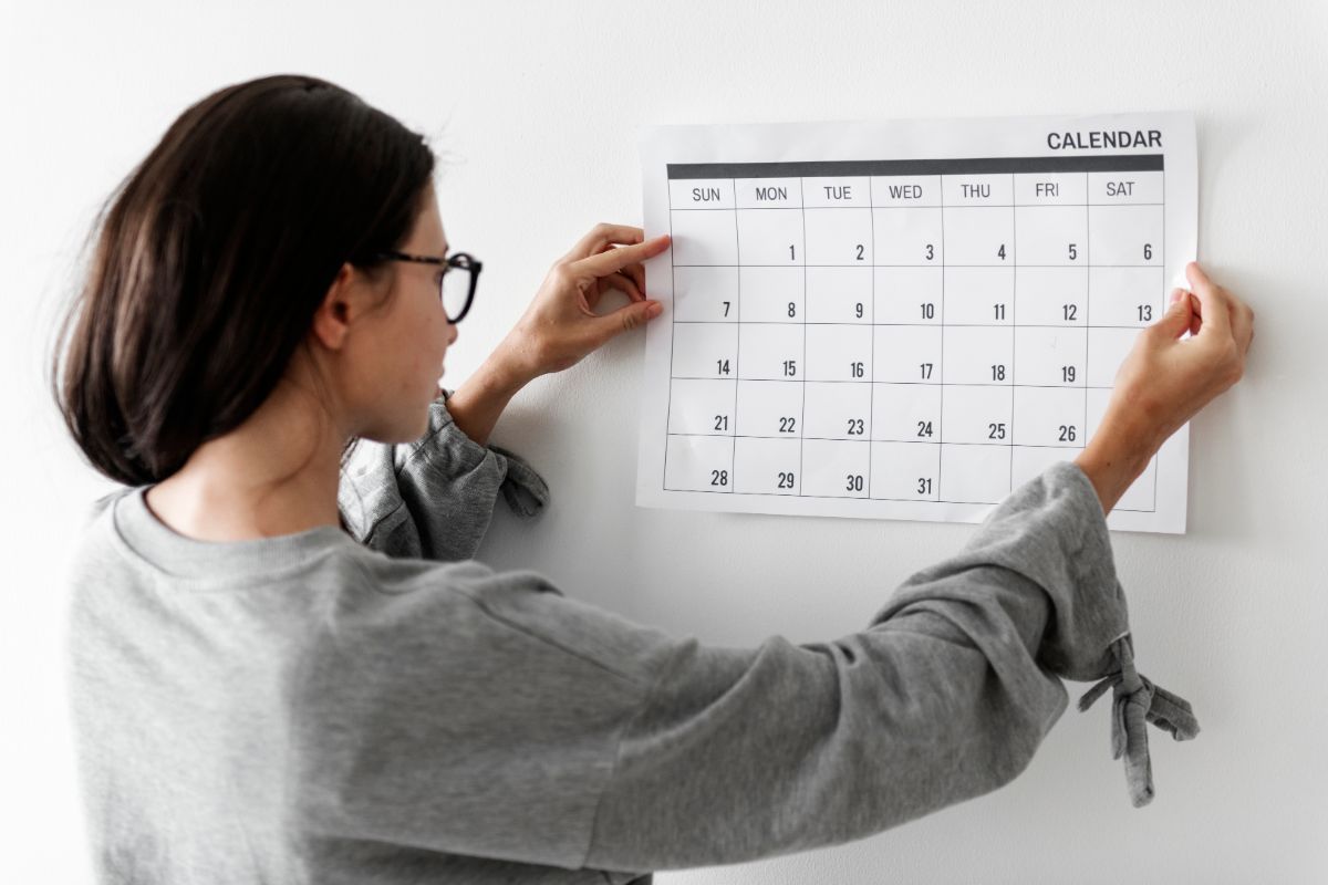 Young woman checking the calendar on a wall.