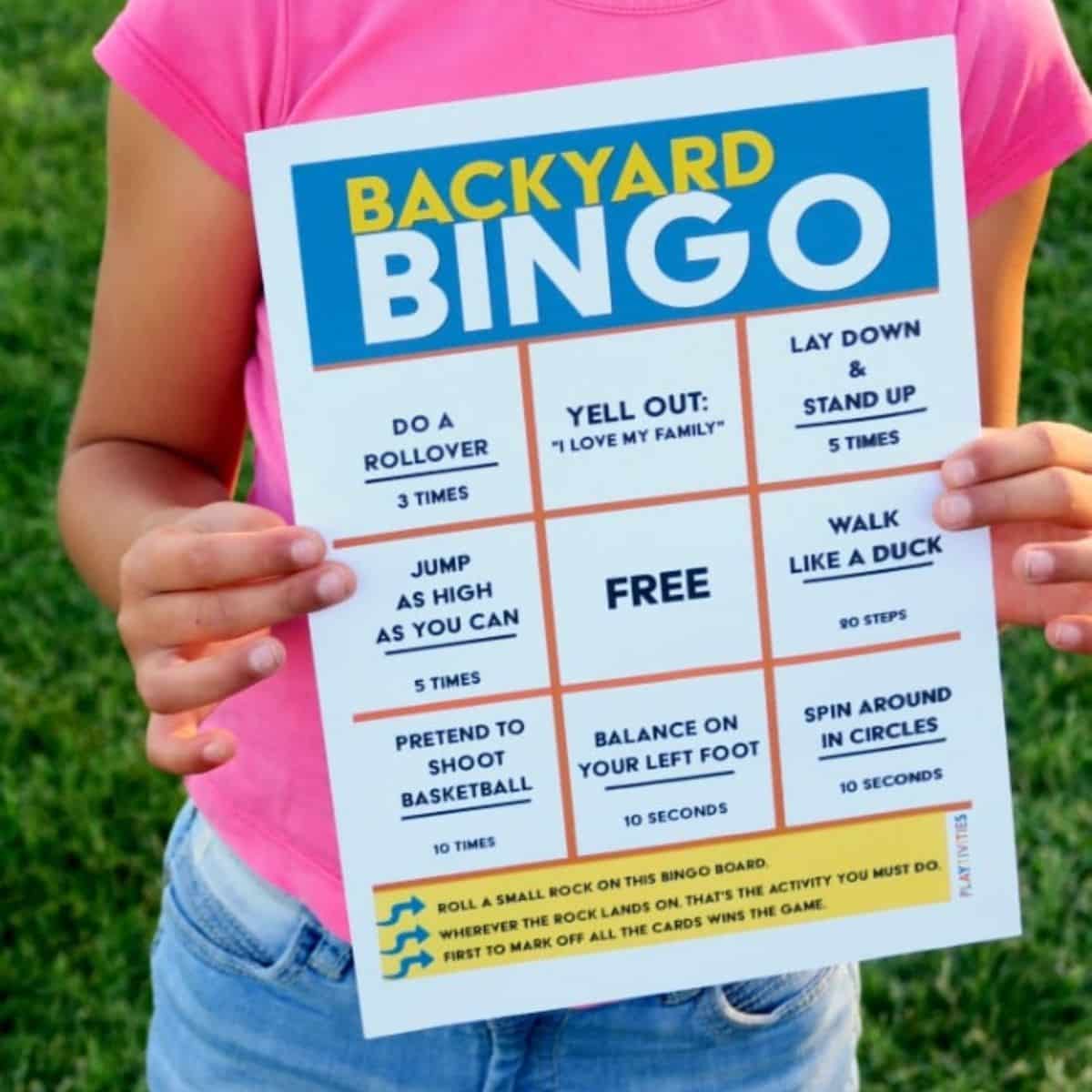 Girl in a pink t-shirt holding a backyard bingo game.
