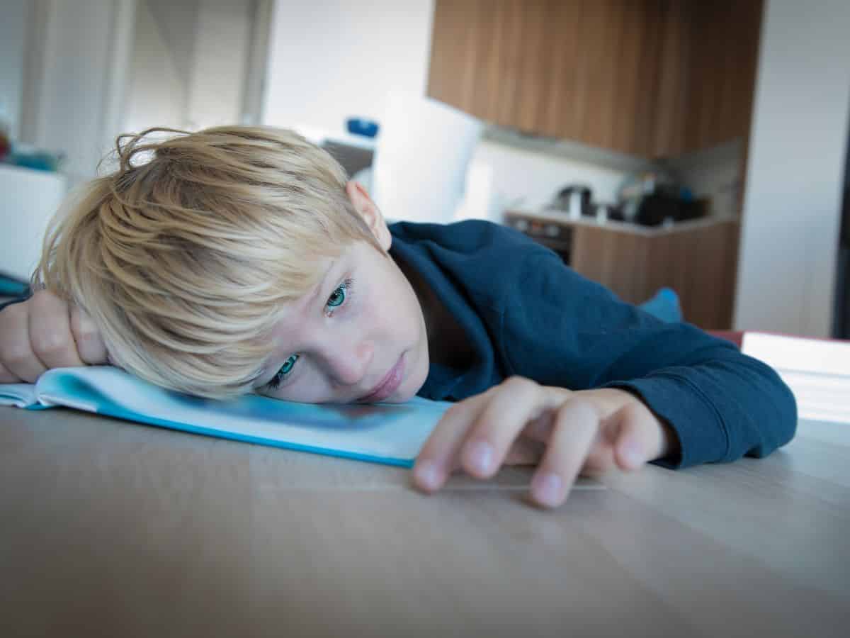 Young boy lying on the floor looking bored.