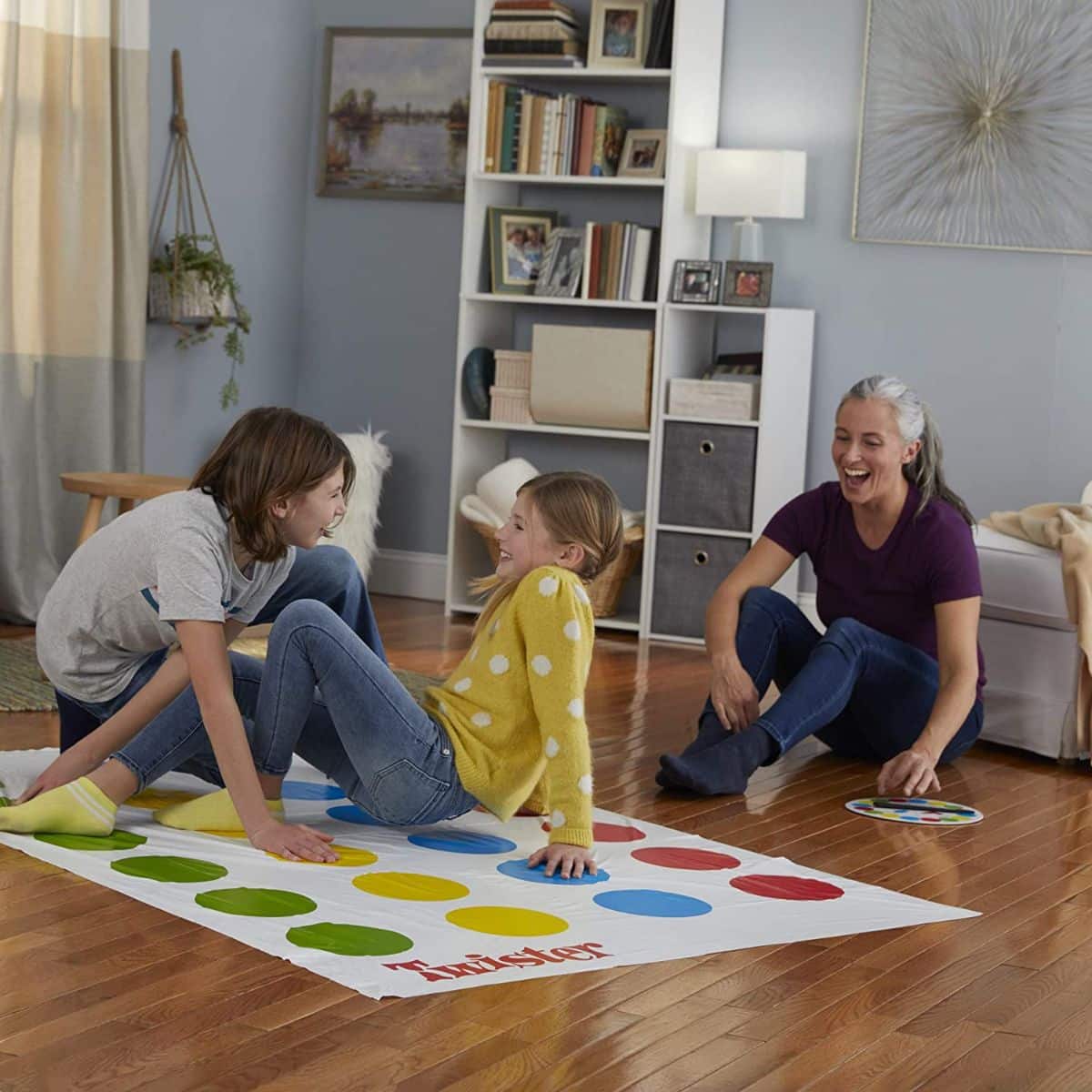 Mother and two kids playing a twister game in the living room.
