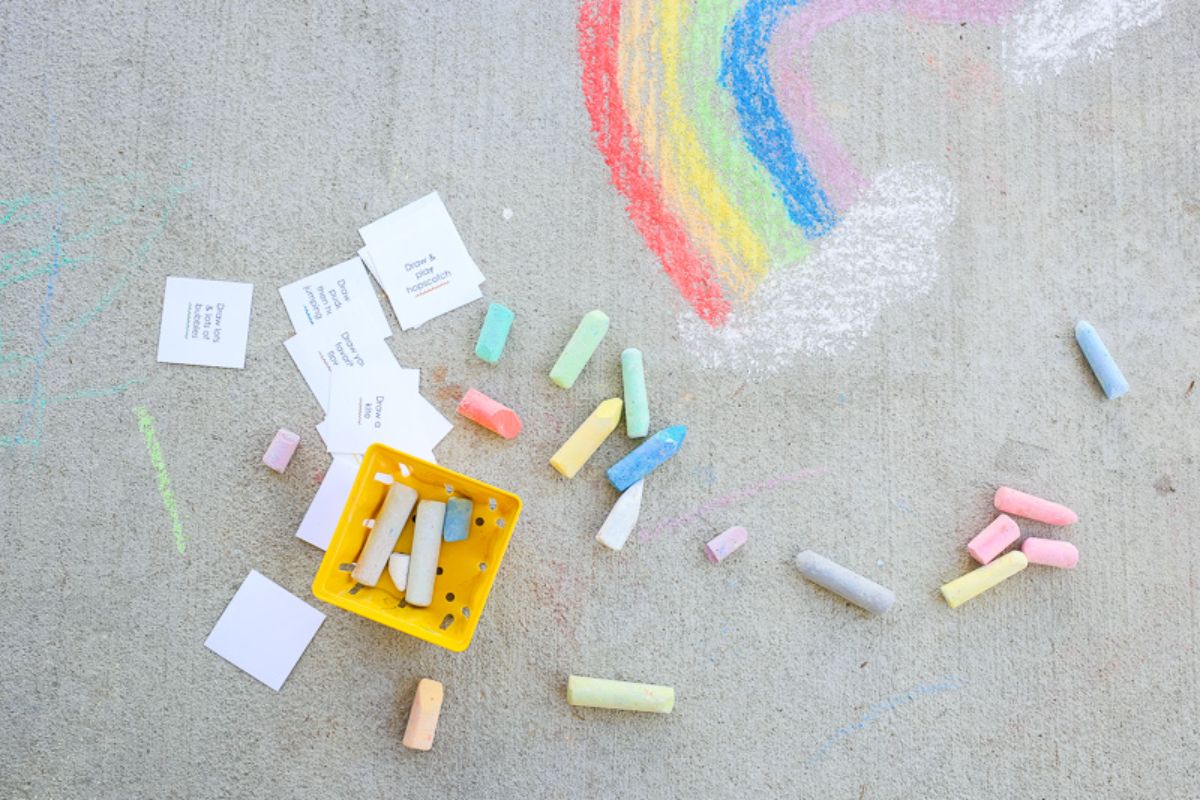 Bunch of colorful chalks, stickers on a sidewalk.